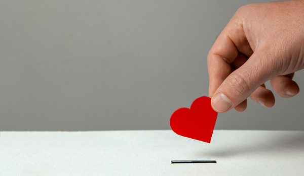 Hand putting a heart shaped card in a box